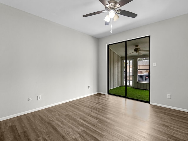 empty room with wood finished floors, a ceiling fan, and baseboards