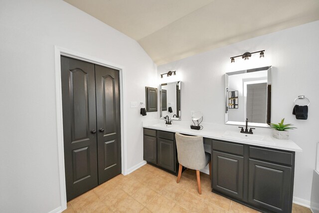 bathroom featuring double vanity, baseboards, lofted ceiling, and a sink