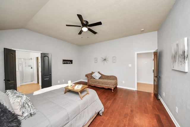 bedroom featuring a ceiling fan, wood finished floors, baseboards, lofted ceiling, and ensuite bath