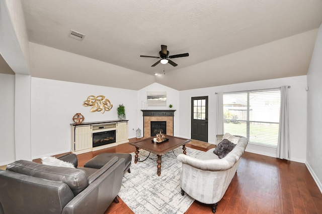 living room featuring a ceiling fan, visible vents, lofted ceiling, a fireplace, and dark wood-type flooring