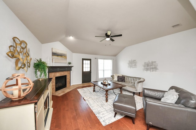 living room with visible vents, ceiling fan, a tile fireplace, vaulted ceiling, and dark wood-type flooring