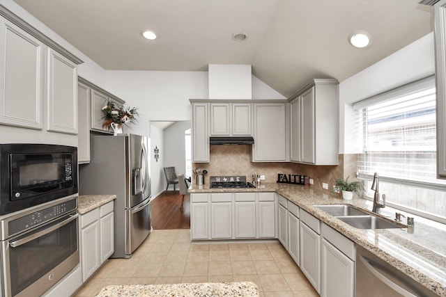 kitchen with a sink, under cabinet range hood, tasteful backsplash, stainless steel appliances, and light tile patterned floors