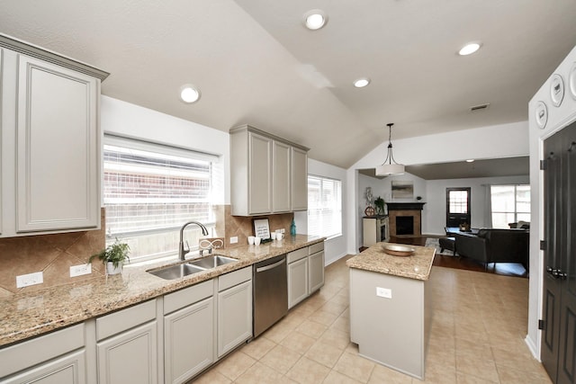 kitchen with a sink, open floor plan, a fireplace, dishwasher, and vaulted ceiling