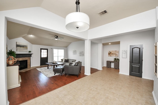 living room with a ceiling fan, wood finished floors, visible vents, lofted ceiling, and a fireplace