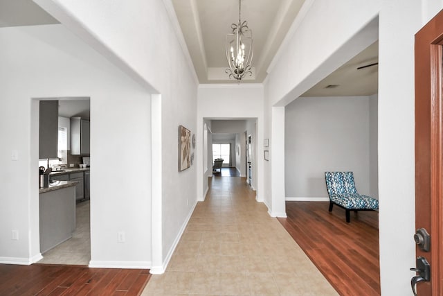 foyer entrance with baseboards, wood finished floors, a chandelier, and crown molding