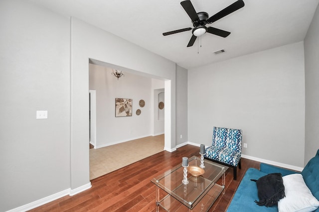 living area featuring visible vents, baseboards, a ceiling fan, and wood finished floors