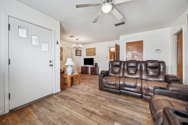 living area with hardwood / wood-style floors, ceiling fan with notable chandelier, and visible vents