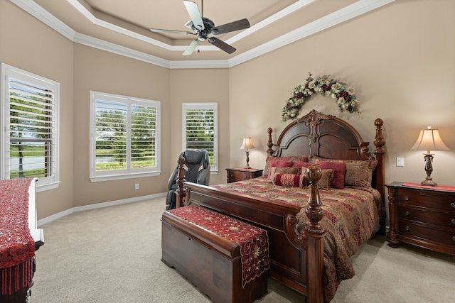 bedroom with a ceiling fan, a tray ceiling, carpet flooring, crown molding, and baseboards