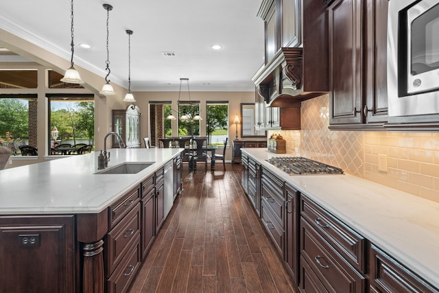 kitchen featuring stainless steel appliances, decorative backsplash, dark wood-type flooring, a sink, and crown molding