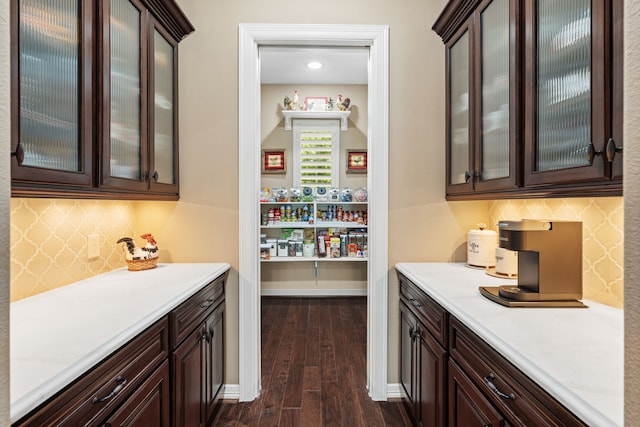 bar featuring baseboards, tasteful backsplash, and dark wood-type flooring