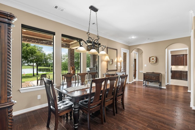 dining space featuring visible vents, ornamental molding, wood finished floors, arched walkways, and baseboards