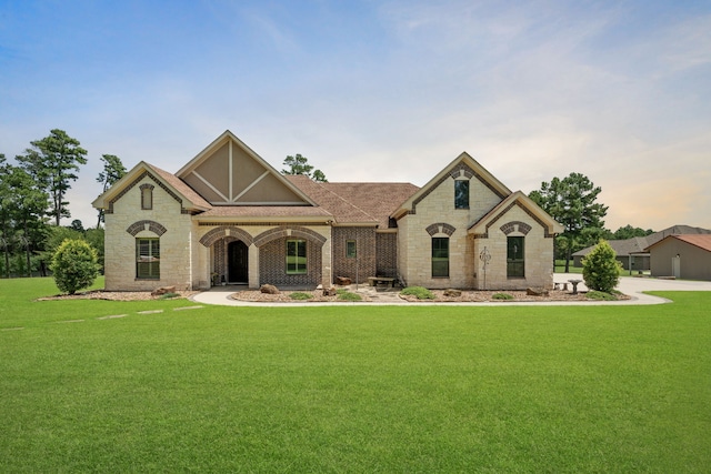 view of front of property with stone siding, brick siding, roof with shingles, and a front lawn