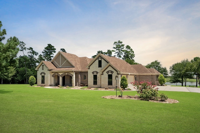 view of front of home with a front lawn, concrete driveway, brick siding, and a garage