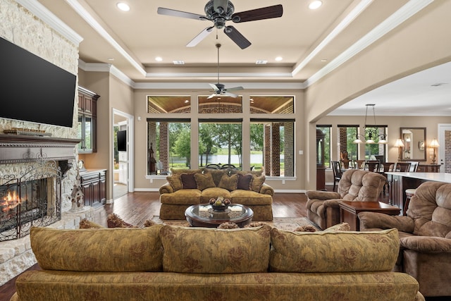 living room featuring a tray ceiling, dark wood-type flooring, ceiling fan, and crown molding