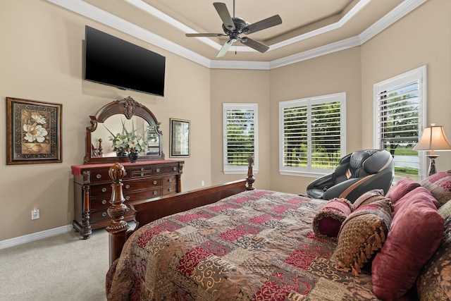 carpeted bedroom with a tray ceiling, baseboards, ornamental molding, and a ceiling fan