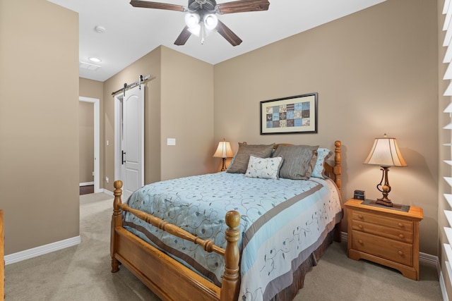 bedroom with a barn door, baseboards, light carpet, and a ceiling fan