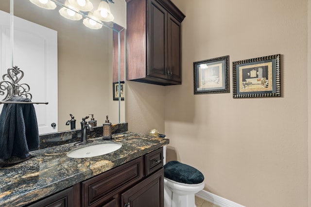 half bathroom featuring vanity, toilet, baseboards, and tile patterned flooring