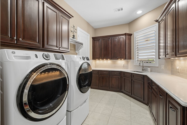 washroom featuring visible vents, a sink, cabinet space, light tile patterned floors, and washing machine and clothes dryer