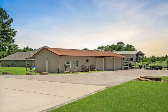 ranch-style house with concrete driveway, a garage, a front lawn, and metal roof