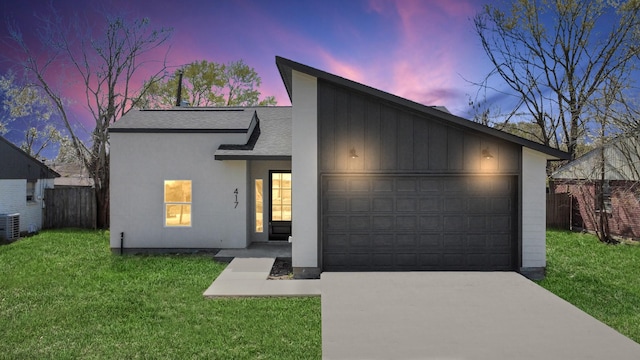 view of front of property featuring an attached garage, a front lawn, fence, roof with shingles, and driveway