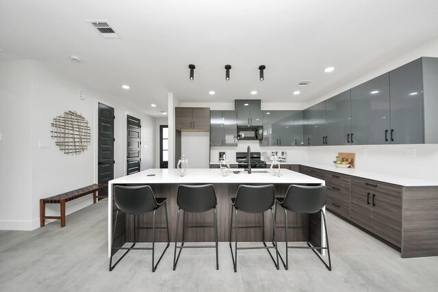 kitchen with visible vents, modern cabinets, a breakfast bar, and black microwave