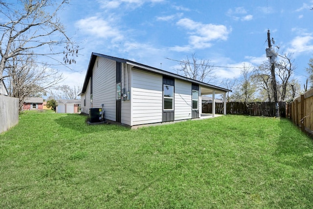 back of house featuring a fenced backyard, a lawn, and central AC