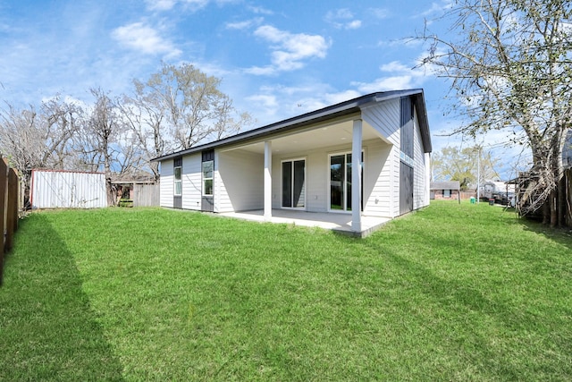 rear view of property with a patio, a lawn, and fence