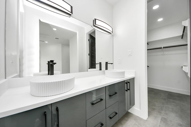 bathroom featuring double vanity, a spacious closet, and a sink