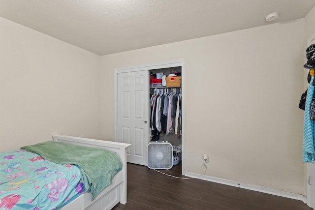 bedroom with dark wood finished floors, a closet, and baseboards