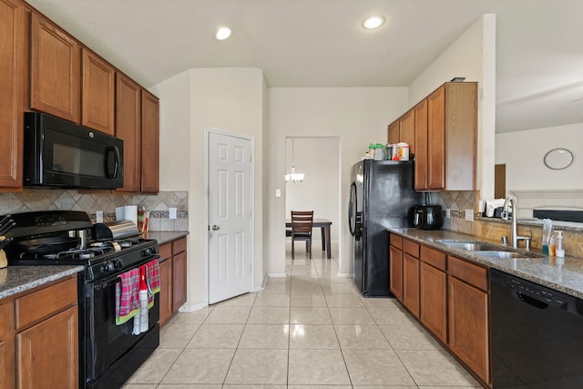 kitchen with backsplash, light tile patterned flooring, brown cabinetry, black appliances, and a sink