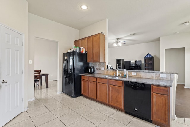 kitchen featuring a peninsula, a sink, black appliances, tasteful backsplash, and brown cabinets