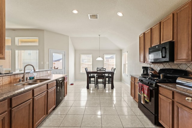 kitchen featuring tasteful backsplash, lofted ceiling, light tile patterned flooring, black appliances, and a sink