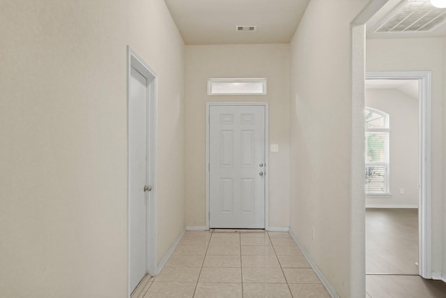 doorway to outside with light tile patterned floors, visible vents, and baseboards