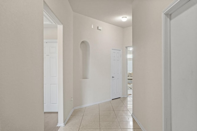 corridor with light tile patterned floors and baseboards