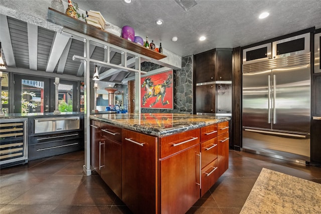 kitchen featuring a center island, beverage cooler, dark stone countertops, a warming drawer, and built in fridge