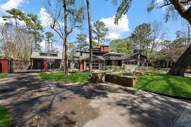 view of front of house featuring a front yard, a gate, fence, and driveway