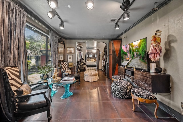 living room featuring tile patterned floors, visible vents, ornamental molding, arched walkways, and rail lighting