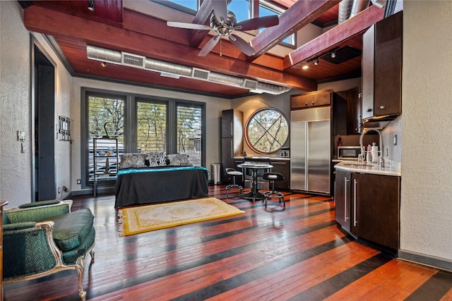 bedroom with beamed ceiling, wood-type flooring, a textured wall, and built in fridge