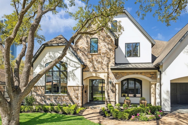 view of front of house with stone siding, stucco siding, metal roof, and a standing seam roof