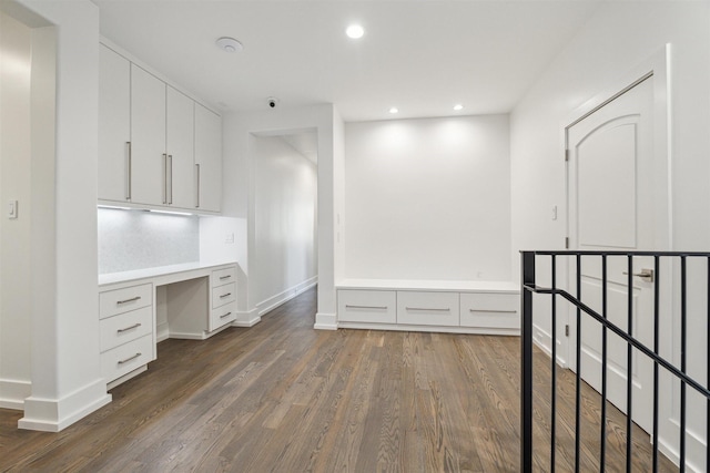 unfurnished office featuring recessed lighting, baseboards, dark wood-style flooring, and built in desk