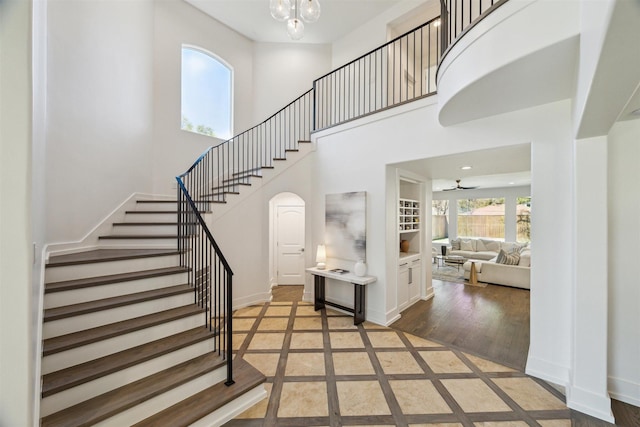 entryway with stairs, a high ceiling, arched walkways, and baseboards