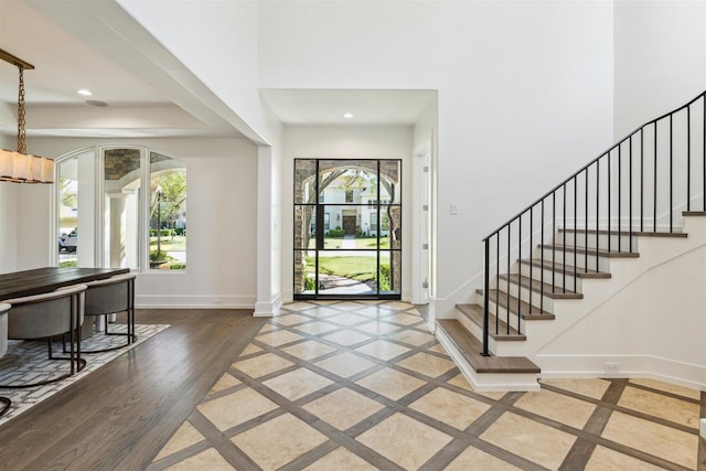 foyer entrance featuring baseboards, stairway, recessed lighting, wood finished floors, and arched walkways