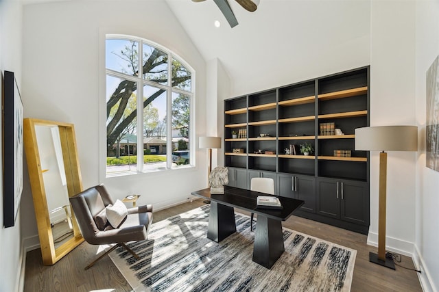 home office with plenty of natural light, dark wood-type flooring, ceiling fan, and high vaulted ceiling