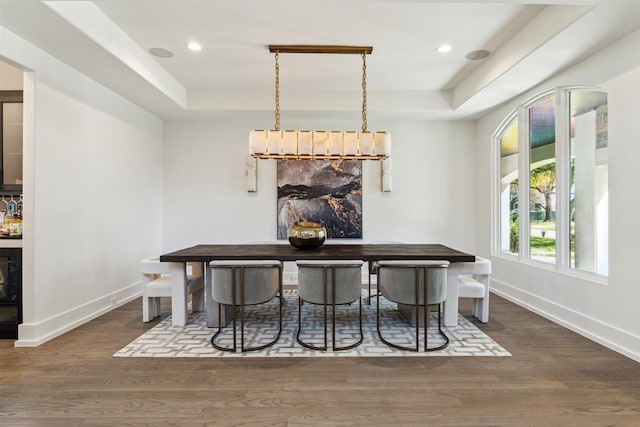 dining space with dark wood finished floors, recessed lighting, baseboards, and a tray ceiling