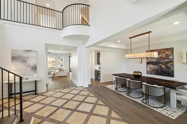 entrance foyer featuring wood finished floors, baseboards, recessed lighting, stairs, and a towering ceiling