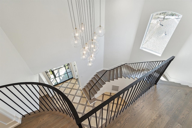 staircase with an inviting chandelier, baseboards, and wood finished floors