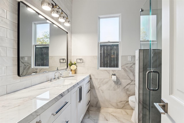 full bath with a shower stall, toilet, vanity, marble finish floor, and tile walls