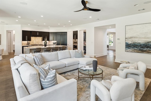 living room featuring a ceiling fan, dark wood-style floors, visible vents, baseboards, and recessed lighting