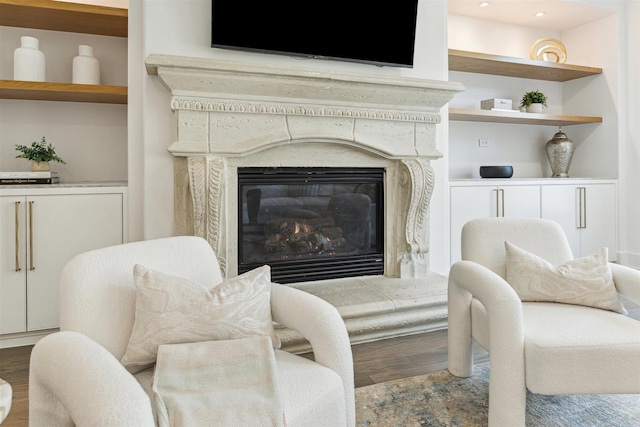 living area featuring built in features, wood finished floors, and a high end fireplace