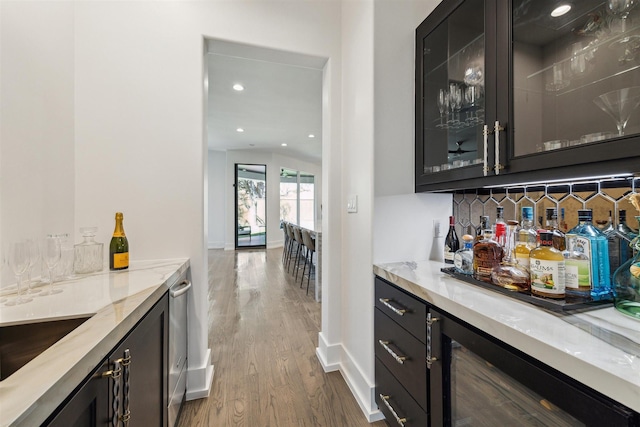 bar with wood finished floors, baseboards, a bar, decorative backsplash, and wine cooler